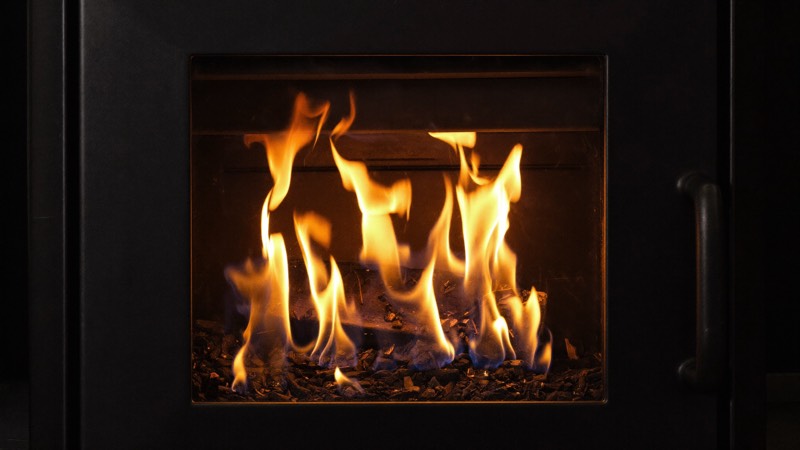 Poêle à granulés moderne avec flamme visible dans un intérieur en pierre