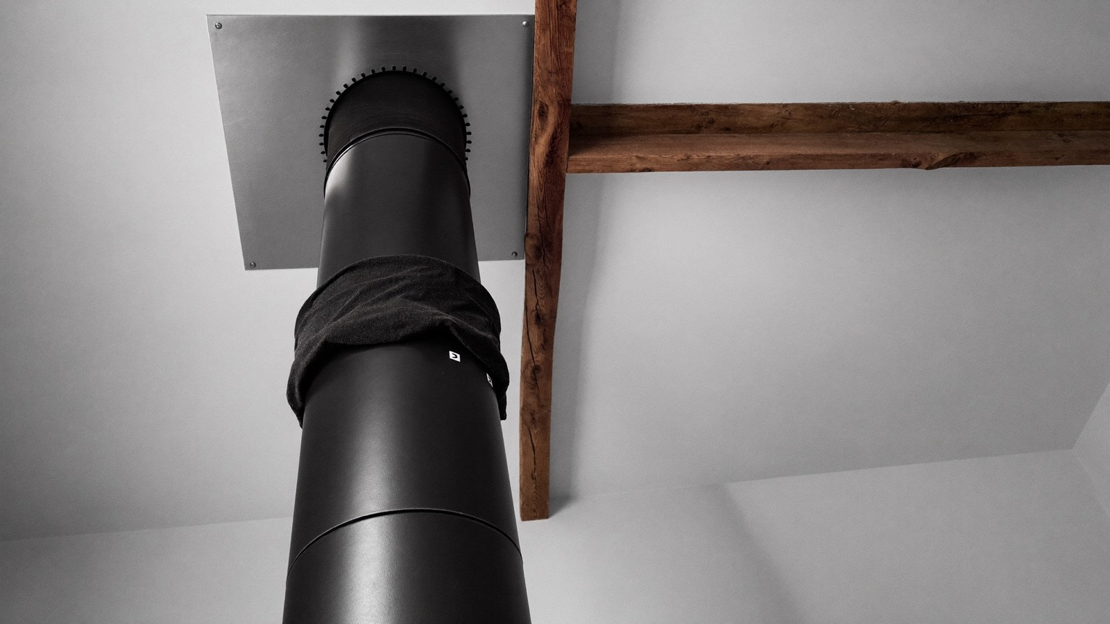 Conduit de fumée isolé traversant un plafond avec sa plaque de finition inox