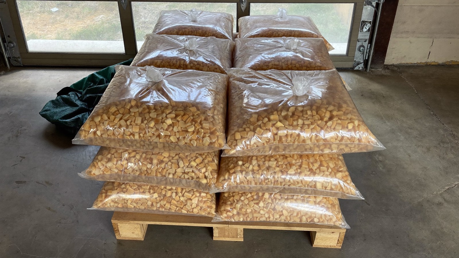 Sacs de granulés de bois empilés sur une palette dans un garage
